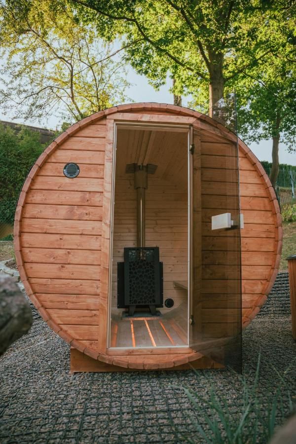 Drewniana sauna w kształcie beczki z przeszklonymi drzwiami i piecem w środku